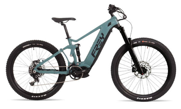 'n Persoon met 'n helm ry bergfiets op 'n grondpad deur 'n digte woud, en leun in 'n skerp draai omring deur hoë bome en gevalle blare.