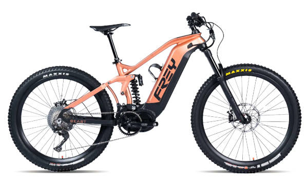 Twee bergfietsryers met helms en brille ry deur 'n modderige, mistige woud, met een fietsryer wat skerp in 'n draai leun, terwyl grond van die roete spat.